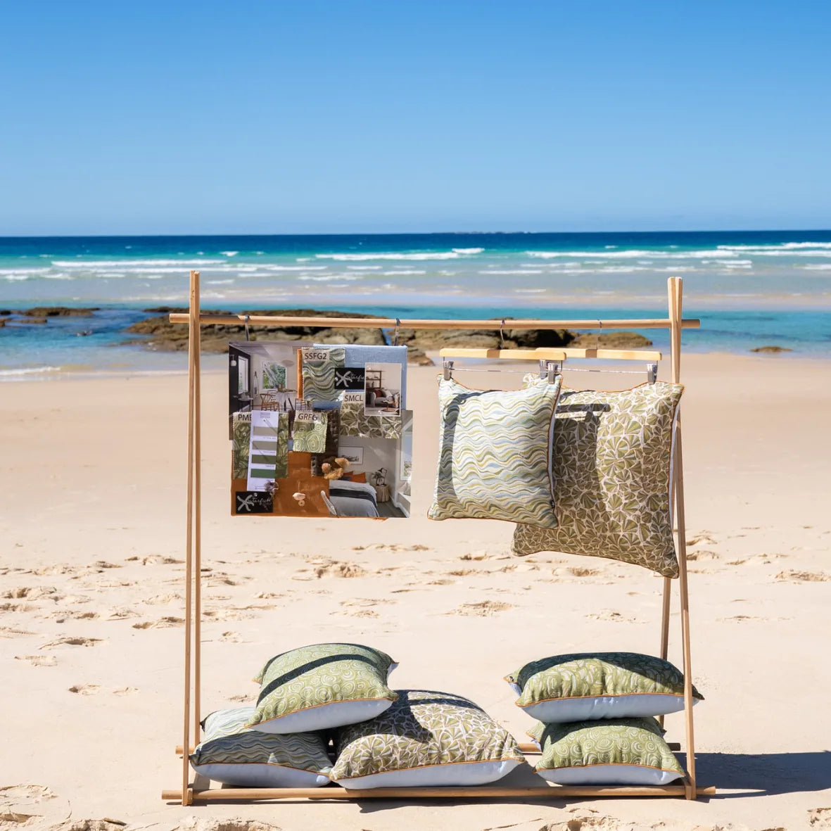 Starfish Studio linen cushion collection displayed on a beach rack with green coastal prints and matching design moodboard.