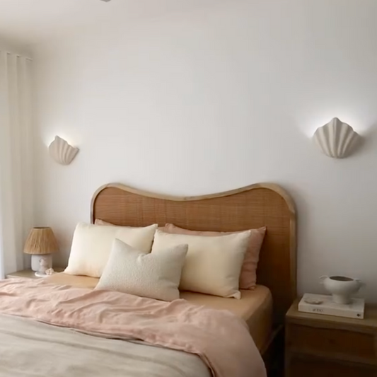 Bedroom with a wooden headboard and pink bedding, featuring two wall sconces.