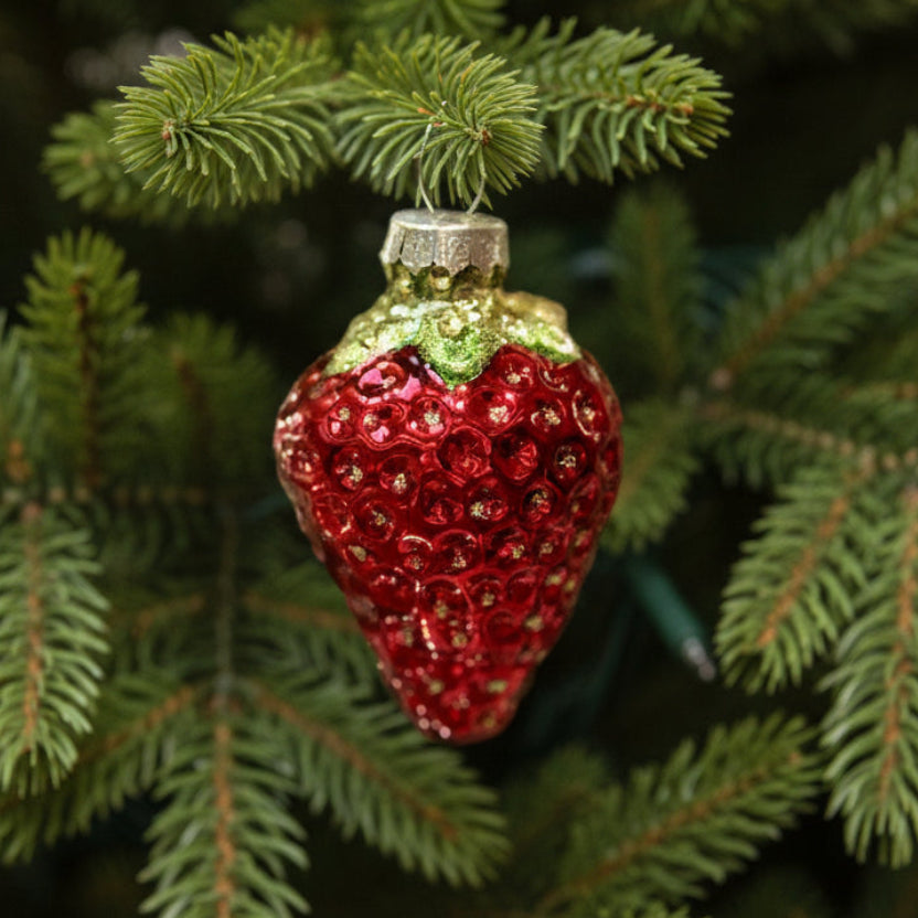Glass strawberry Christmas ornament hanging on a Christmas tree