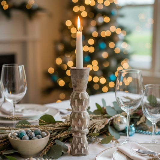 Large white washed candle holder with a lit candle on a Christmas table