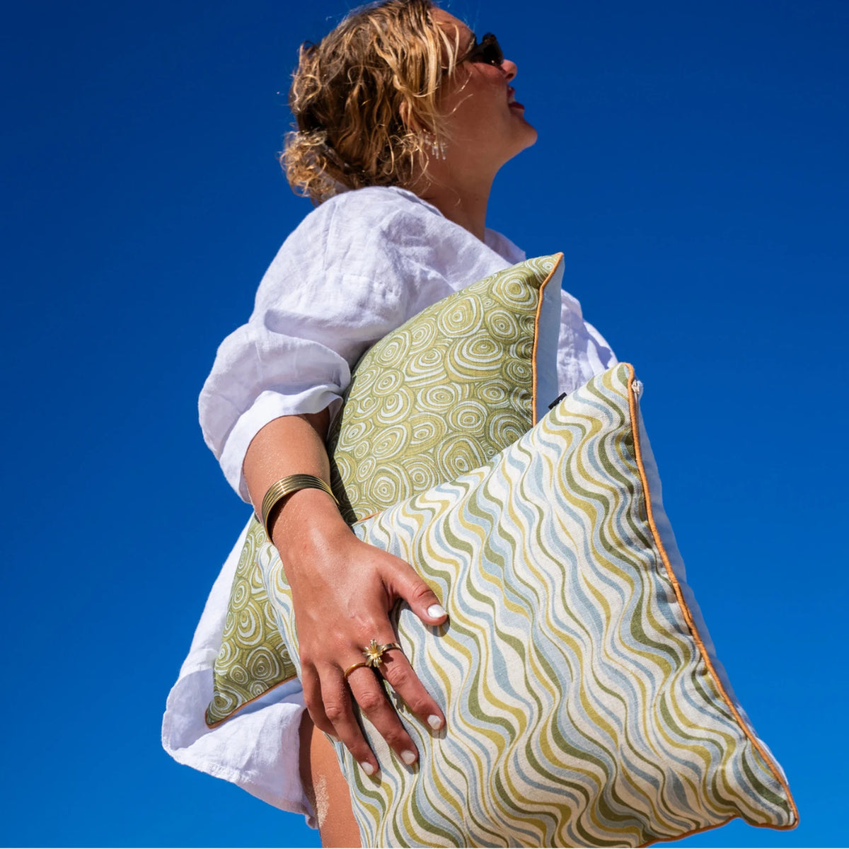 Woman holding Mangrove linen cushion covers in Growth Rings and Straddie Stripe coastal prints
