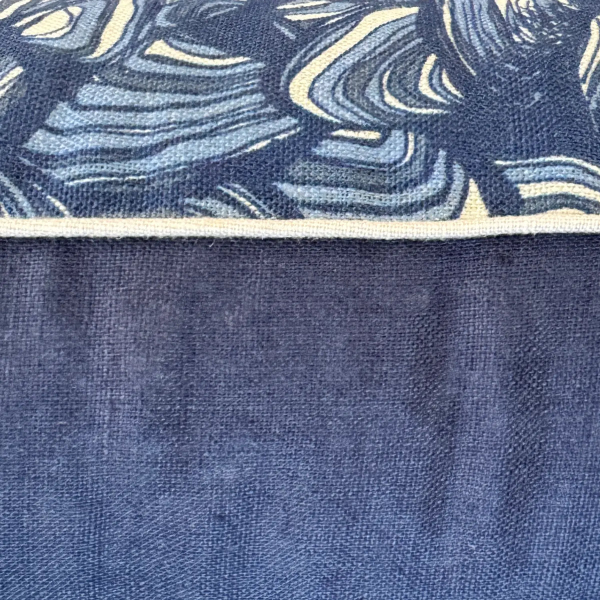Close-up of Pacific Pipi linen cushion cover showing blue print, natural piping and navy linen reverse
