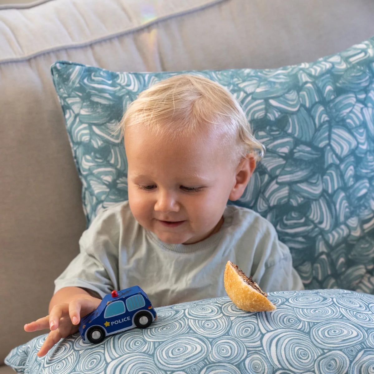 Child playing on a lounge with Frenchmans colourway cushions featuring the Pipi pattern and the Growth Rings pattern.