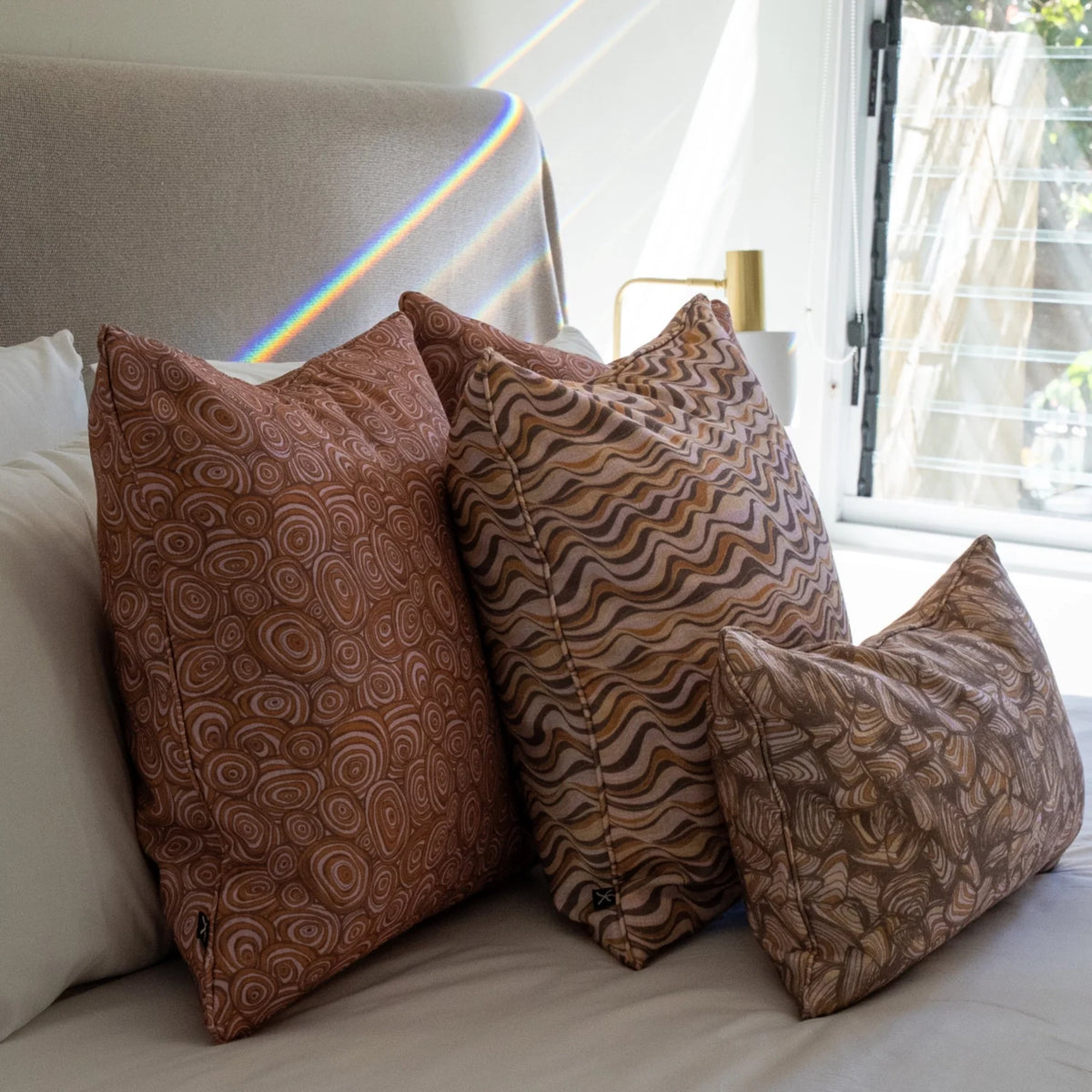 Claytons cushion covers featuring Straddie Stripe, Growth Rings and Pipi prints styled together in a coastal bedroom.