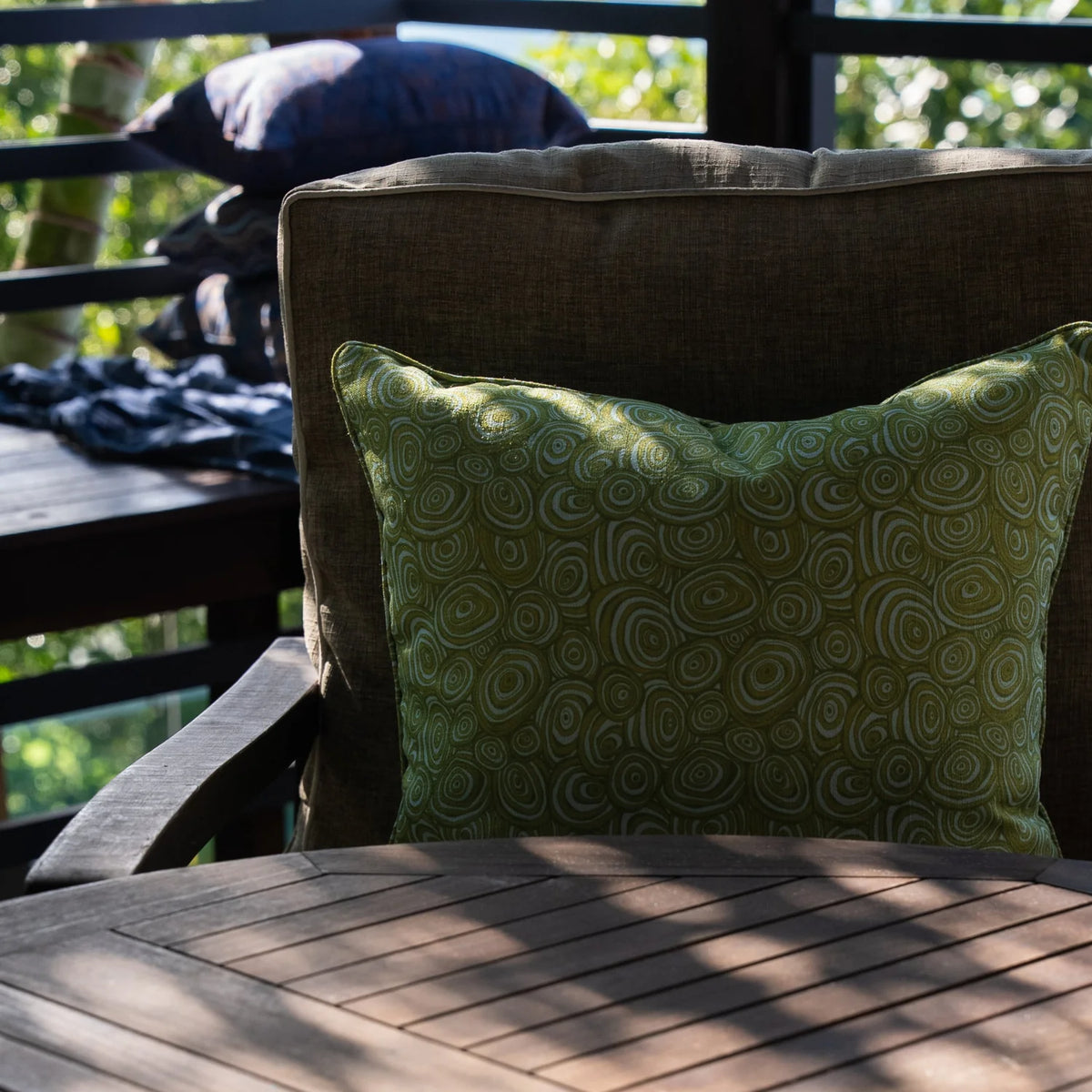 Outdoor Indoor Growth Rings cushion cover in Mangrove on a linen armchair, outdoor balcony setting